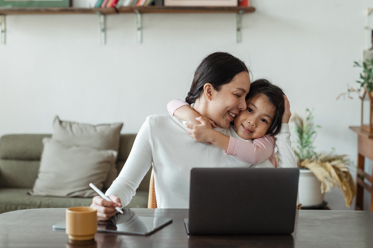 madre trabajando abrazando a hija